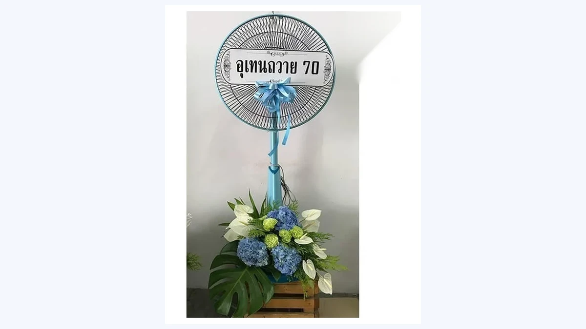 พวงหรีดพัดลมที่ตั้งหน้าศาลาพร้อมป้ายชื่อผู้ส่งในนามกลุ่ม ซึ่งเป็นรูปแบบที่ทีมงานหรือรุ่นนิยมส่งร่วมกัน