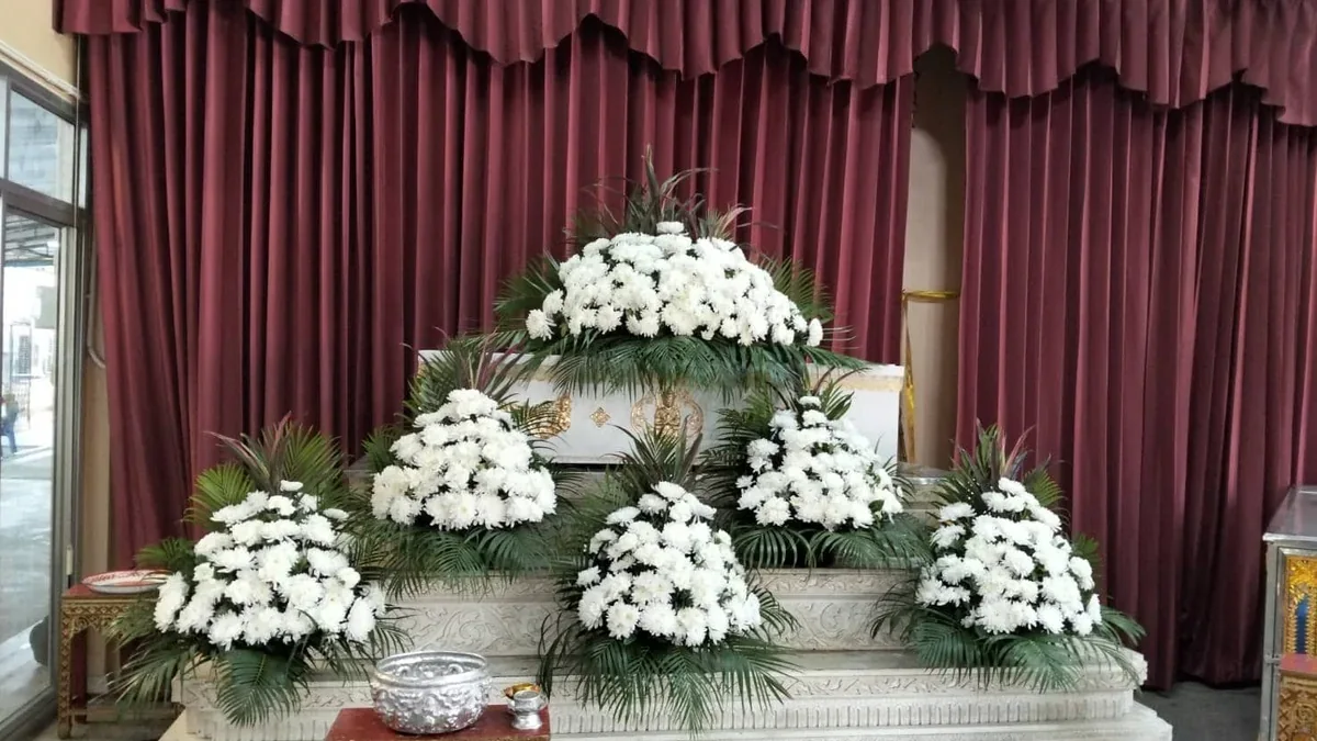 แท่นตั้งศพประดับดอกไม้สดโทนขาวในศาลาวัด สำหรับพิธีรดน้ำศพและตั้งสวดพระอภิธรรม